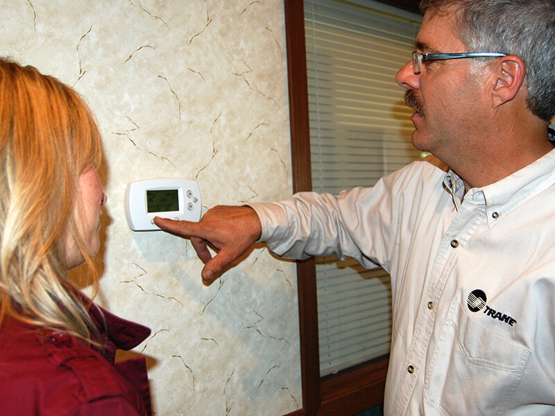 Showing a office worker the use of a new thermostat installed by Viking Mechanical.